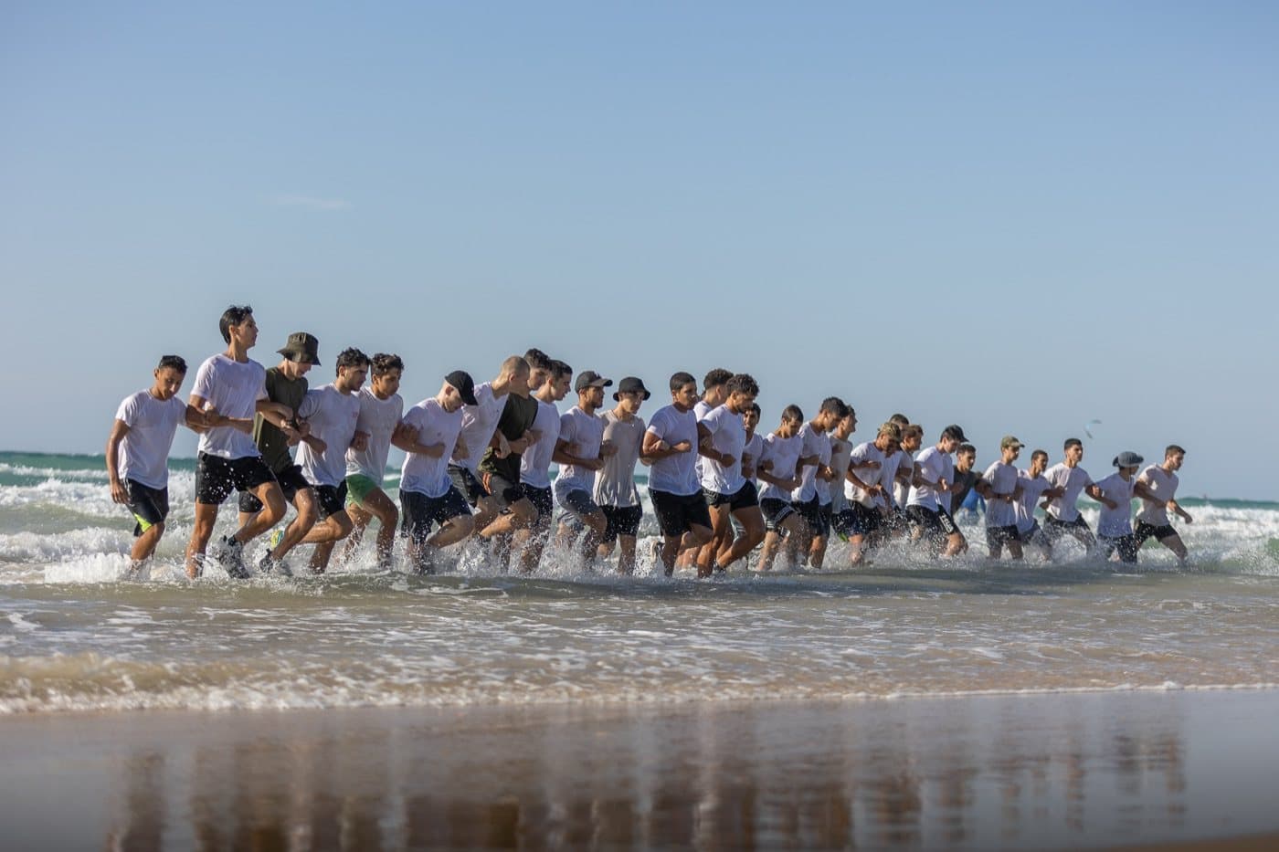 שורה ארוכה של חניכי אדרנלין כושר קרבי רצים אל תוך הים