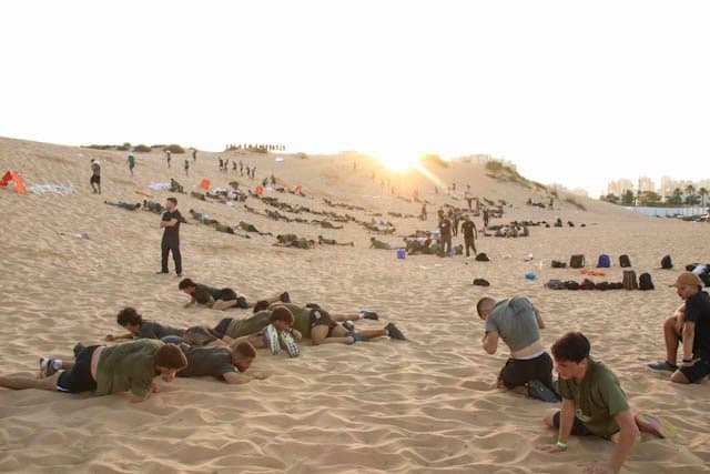 חניכי אדרנלין כושר קרבי זוחלים על דיונה מול שמש נמוכה