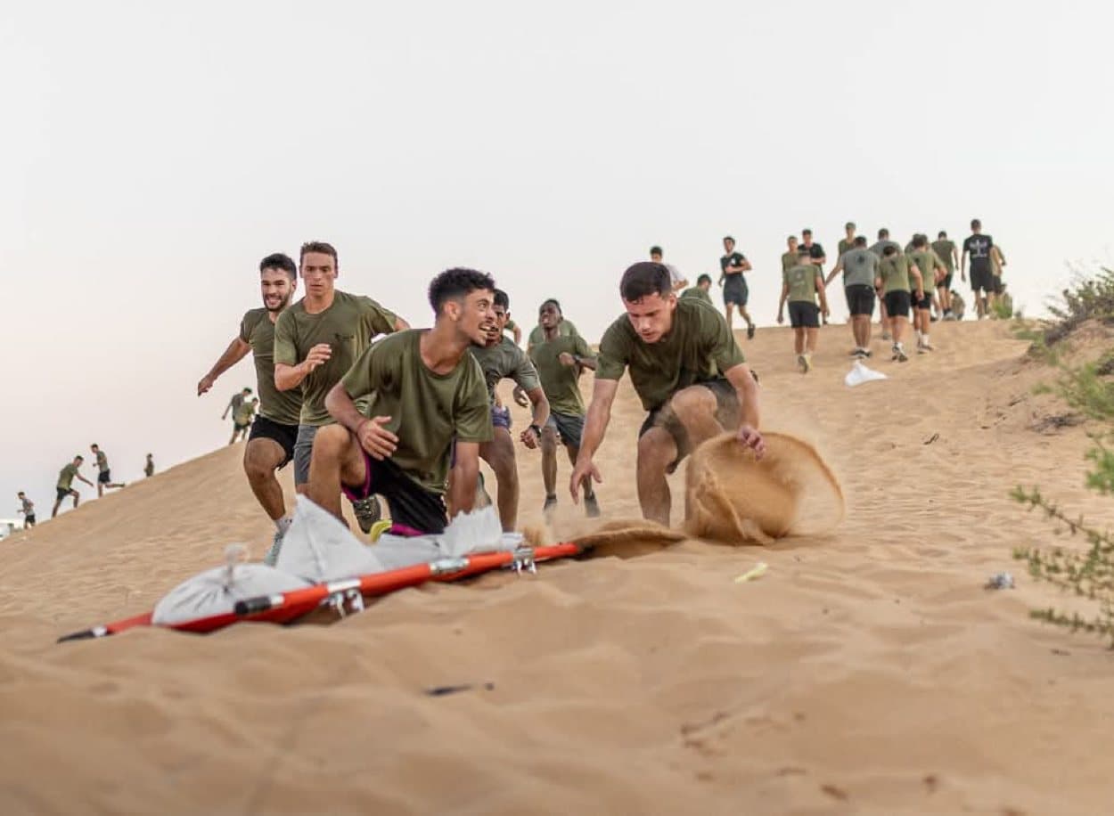 חניכי אדרנלין כושר קרבי מזנקים על דיונה אל אלונקה עמוסה בשקי חול